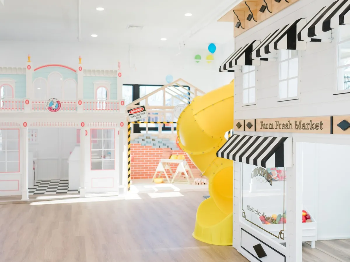 Pretend-play storefronts and a yellow slide at Imagination Street
